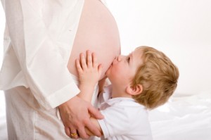 child kissing mom's pregnant belly