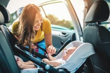 mom putting baby in car seat