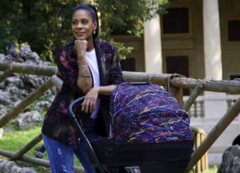 woman sitting on a bench looking while holding the handle of a stroller