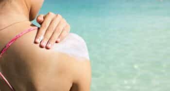 Girl applying sun lotion on the beach