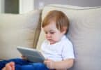 baby watching cartoon on digital tablet sitting on the sofa