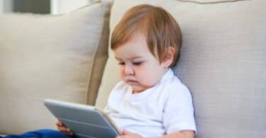 baby watching cartoon on digital tablet sitting on the sofa