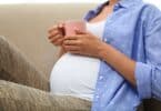 Young pregnant woman holding her tummy at home