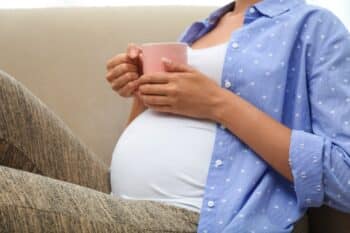 Young pregnant woman holding her tummy at home