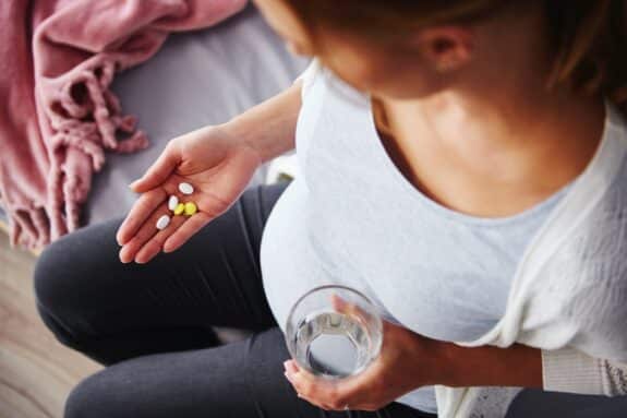 Young pregnant woman taking medicine