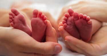 hands cradling twin babies' feet