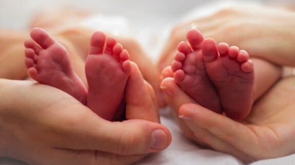 hands cradling twin babies' feet