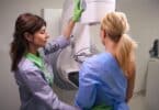 Experienced radiologic technologist preparing female for mammogram