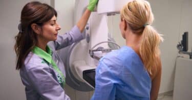 Experienced radiologic technologist preparing female for mammogram