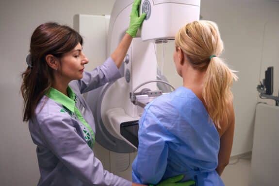 Experienced radiologic technologist preparing female for mammogram