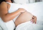 Pregnant woman embracing her belly while resting in bed