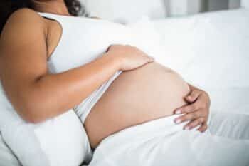 Pregnant woman embracing her belly while resting in bed