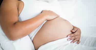 Pregnant woman embracing her belly while resting in bed