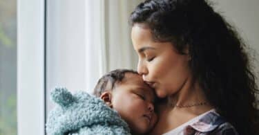 young mother giving her baby a kiss at home