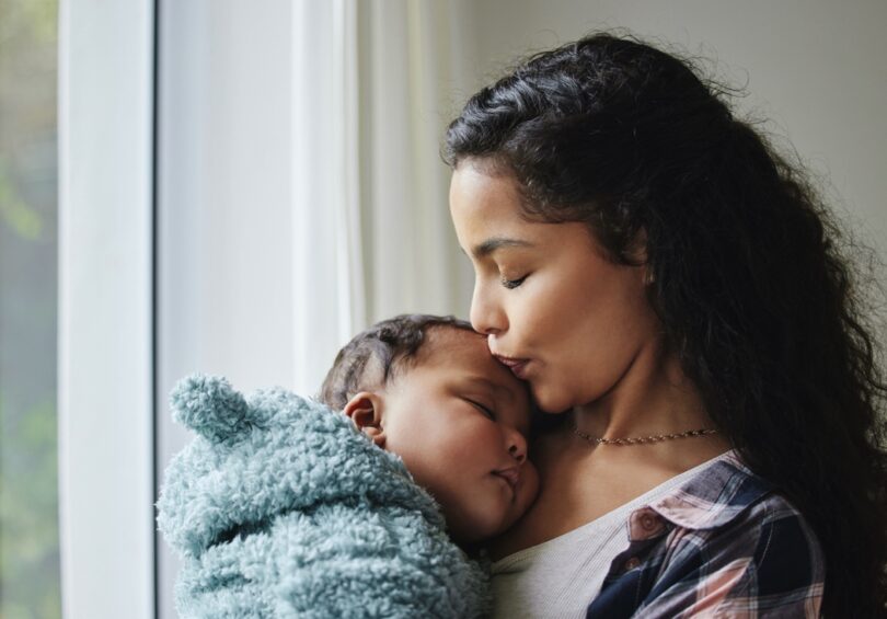 young mother giving her baby a kiss at home